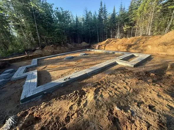 Semelles de fondation alignées sur un terrain boisé